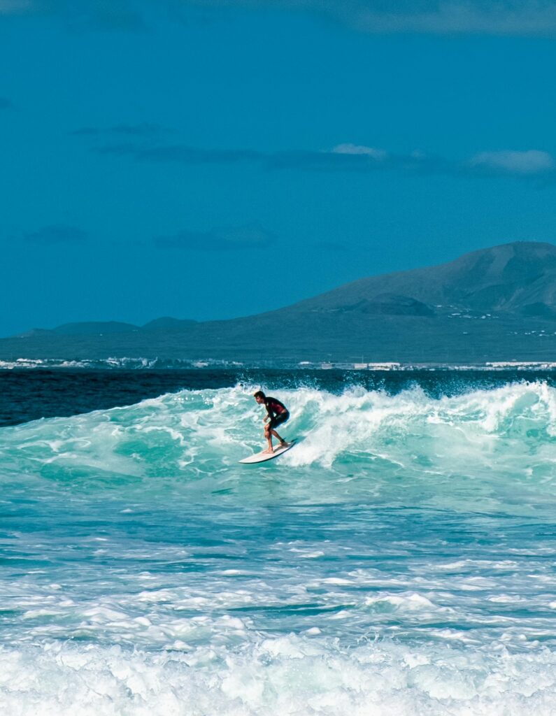 Surfer riding a turquoise wave off the coast of the Canary Islands