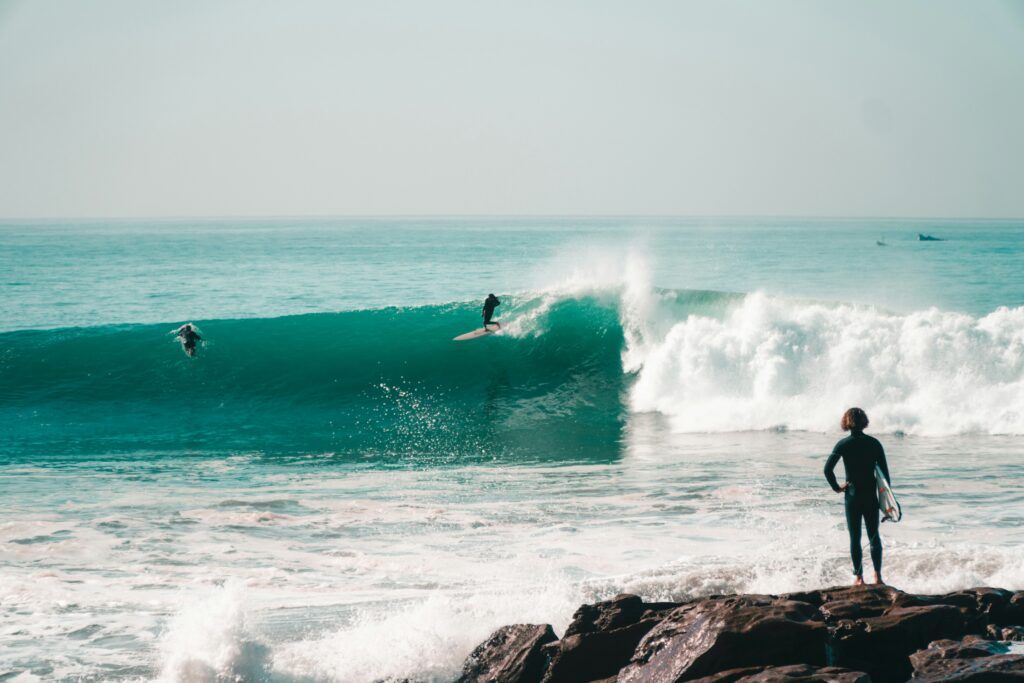 Surfer riding a large, powerful turquoise point break wave in winter, Tamraght surf spot.