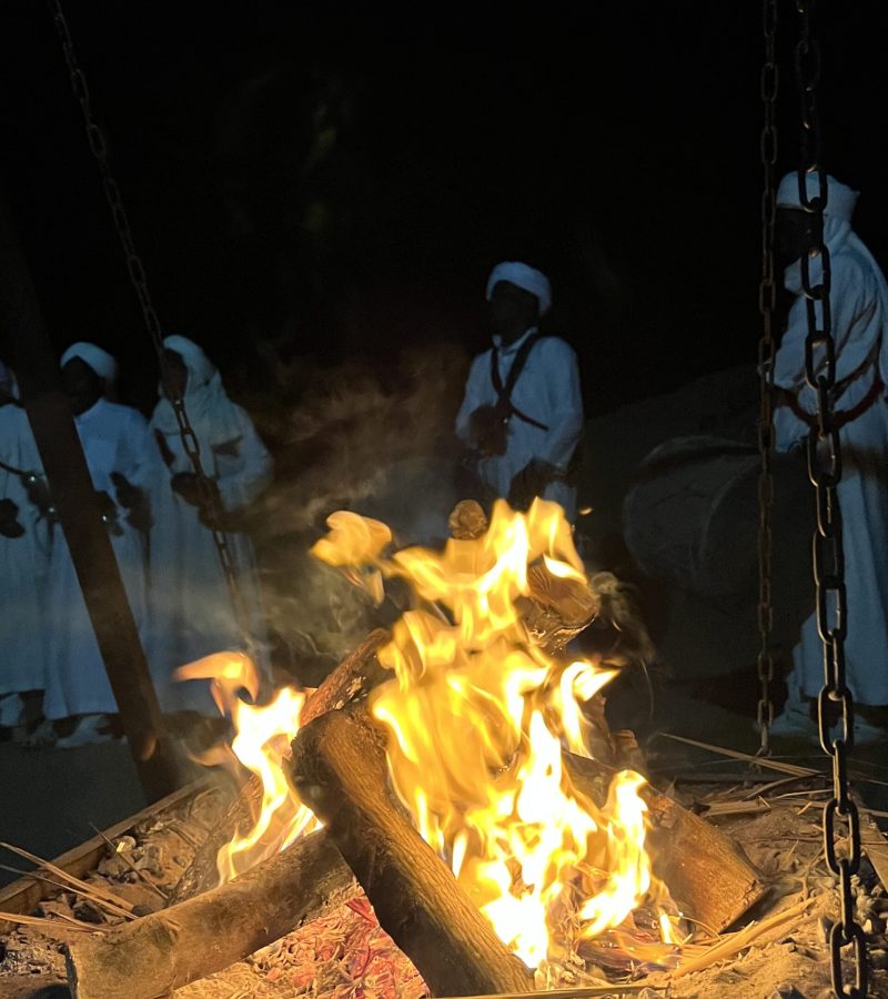 People around a campfire in Moroccan desert at night.