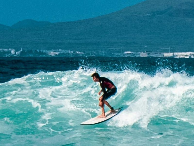 Surfer riding a turquoise wave off the coast of the Canary Islands